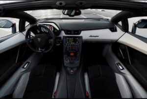 Matte black Lamborghini Aventador Ultimae parked on Dubai bridge with skyline view.