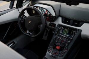 Matte black Lamborghini Aventador Ultimae parked on Dubai bridge with skyline view.