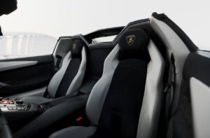 Matte black Lamborghini Aventador Ultimae parked on Dubai bridge with skyline view.