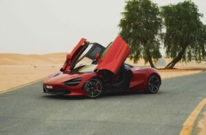 Red McLaren 720S 2024 with butterfly doors open in desert road